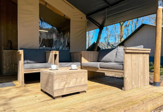 Tienda safari de lujo con terraza y muebles de madera en Camping De Betteld, Países Bajos, soleado.