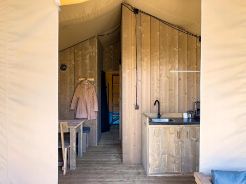 Vista interna di una tenda safari di lusso con bagno privato e cucina presso Camping De Betteld nei Paesi Bassi.