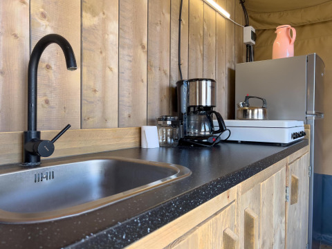 Angolo cucina in tenda safari di lusso al Camping De Betteld con lavandino, fornello e caffettiera.