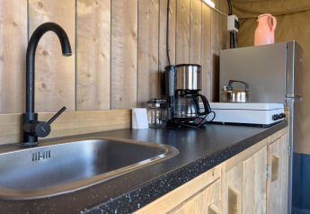 Køkkenområde i luksus safaritelt på Camping De Betteld med vask, kogeplader og kaffemaskine.