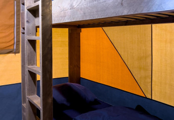 Lit superposé en bois avec literie sombre dans une tente safari de luxe au Camping De Betteld, Pays-Bas.