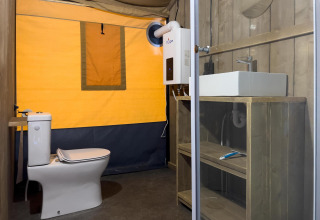Moderne badkamer in een luxe safaritent met toilet en wastafel bij Camping De Betteld in Nederland.