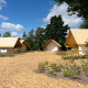 Vista de tiendas glamping en el lodge Kiezel en Zilverstrand, Bélgica, rodeadas de árboles y cielo azul.