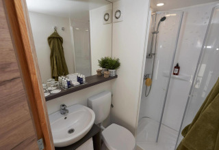Moderne badeværelse på Kiezel-lodgen på Zilverstrand i Belgien med bruser, toilet og håndvask.