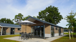 Modern Velthorst lodge at Zilverstrand in Belgium featuring a patio, outdoor dining set, and umbrella.