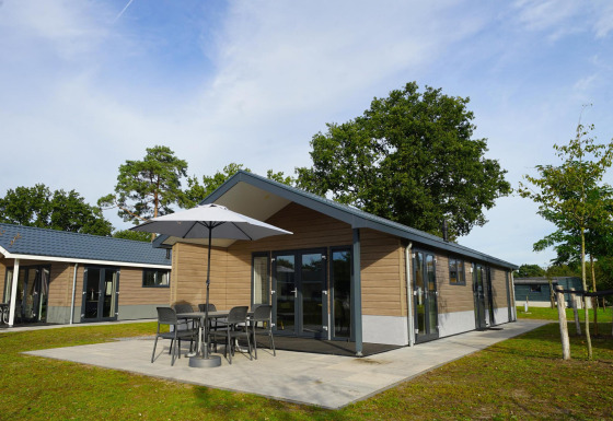 Moderne Lodge Velthorst am Zilverstrand in Belgien mit Außenterrasse, Tisch und Sonnenschirm.