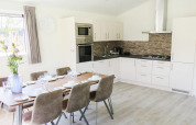 Moderne spise- og køkkenområde på Velthorst-lodge, Zilverstrand, Belgien, med plads til seks personer.