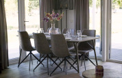 Mesa comedor con seis sillas y un jarrón de flores en Velthorst Lodge de Zilverstrand, Bélgica, ambiente luminoso.