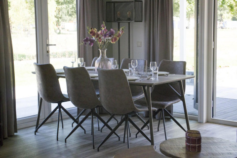 Esstisch mit sechs Stühlen und Blumen in einer Vase in der Velthorst-Lodge am Zilverstrand in Belgien.