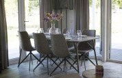 Dining table with six chairs and a flower vase at Velthorst lodge in Zilverstrand, Belgium, bright setting.