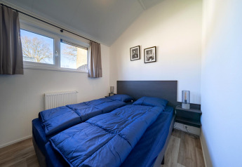 Chambre avec deux lits simples et une literie bleue au lodge Velthorst à Zilverstrand, en Belgique.