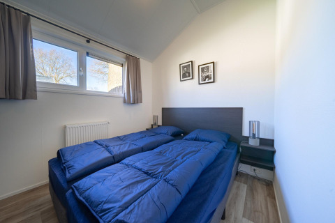 Schlafzimmer mit zwei Einzelbetten und blauer Bettwäsche in der Velthorst Lodge am Zilverstrand, Belgien.