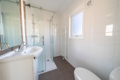 Modernes Badezimmer in der Velthorst-Lodge am Zilverstrand in Belgien mit Dusche, Waschbecken und Fenster.
