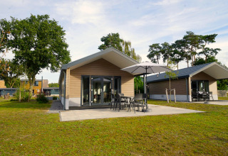 Lodge Velthorst à Zilverstrand en Belgique avec chalets modernes, terrasse et mobilier de jardin sous parasol.