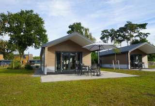 Velthorst-Lodge am Zilverstrand in Belgien mit modernen Hütten und Terrasse mit Sonnenschirm und Stühlen.