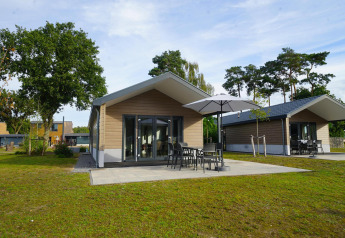 Velthorst-lodge op Zilverstrand in België met moderne huisjes, terras en tuinmeubilair met grote parasol.