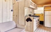 Vue intérieure de la tente safari Villatent Outback avec murs en bois clair, cuisine et réfrigérateur.