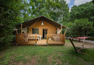 Safari telt Villatent Nomad med træterrasse og hængekøje på Camping La Clémentine omgivet af grønne træer.