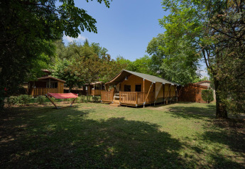 Tente safari Villatent Nomad au Camping La Clémentine en France, avec terrasse, arbres et hamac dans le jardin.