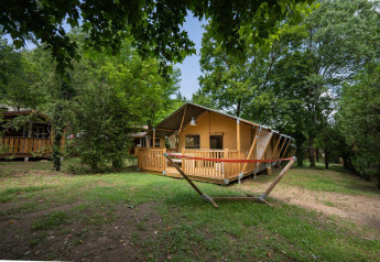 Safari-Zelt Villatent Nomad auf Camping La Clémentine in Frankreich, umgeben von grünen Bäumen.