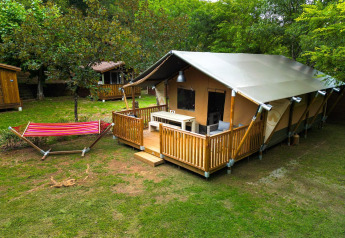 Safari-teltet Villatent Nomad med terrasse og hængekøje på Camping La Clémentine i Frankrig, omgivet af træer.