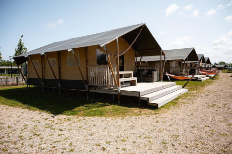 Tiendas safari de Villatent Nomad en RCN de Schotsman, Países Bajos, con terraza, hamacas y muebles de exterior.