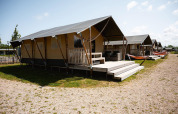 Tiendas safari de Villatent Nomad en RCN de Schotsman, Países Bajos, con terraza, hamacas y muebles de exterior.