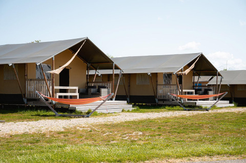 Safari tents with porches and hammocks at Villatent Nomad, RCN de Schotsman, Netherlands, on a sunny day.