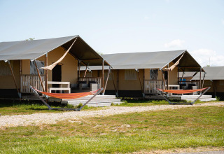 Tiendas safari con porches y hamacas en Villatent Nomad, RCN de Schotsman, Países Bajos, en un día soleado.