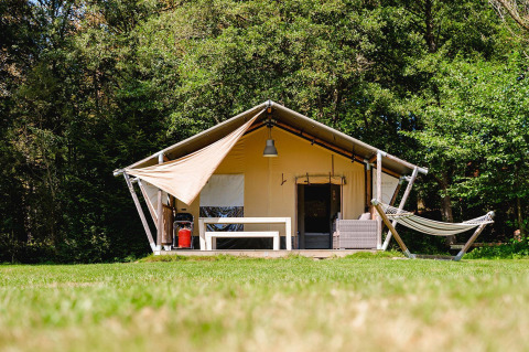Safari-Zelt Villatent Wood auf Camping Au Clos de La Chaume in Frankreich mit Hängematte und Terrasse vorne.