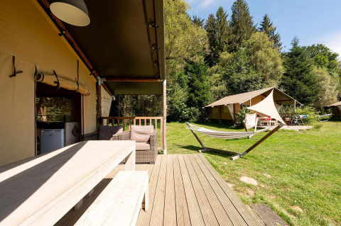 Safaritent Villatent Wood bij Camping Au Clos de La Chaume in Frankrijk met houten terras en hangmat.