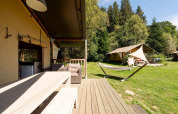Safaritent Villatent Wood bij Camping Au Clos de La Chaume in Frankrijk met houten terras en hangmat.