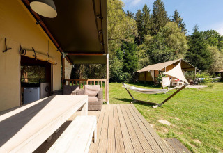 Tienda safari Villatent Wood en Camping Au Clos de La Chaume, Francia, con terraza y hamaca al aire libre.