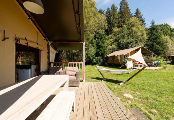 Safaritent Villatent Wood bij Camping Au Clos de La Chaume in Frankrijk met houten terras en hangmat.