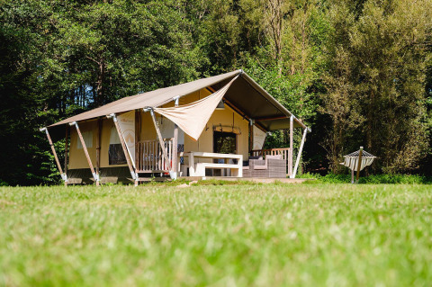 Tienda safari Villatent Wood en Camping Au Clos de La Chaume, Francia, rodeada de naturaleza verde y tranquila.