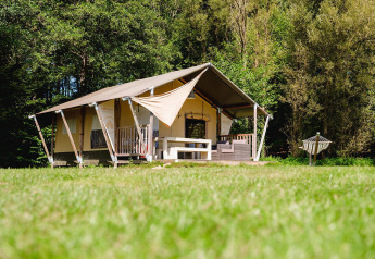 Tente safari Villatent Wood au Camping Au Clos de La Chaume en France, entourée de verdure et d'arbres.
