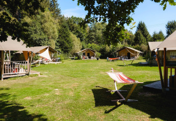 Tiendas safari y hamacas sobre césped en Villatent Wood, Camping Au Clos de La Chaume, Francia.