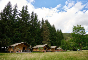 Tentes safari Villatent Wood au Camping de Vaubarlet en France, entourées d’arbres et de prairie.