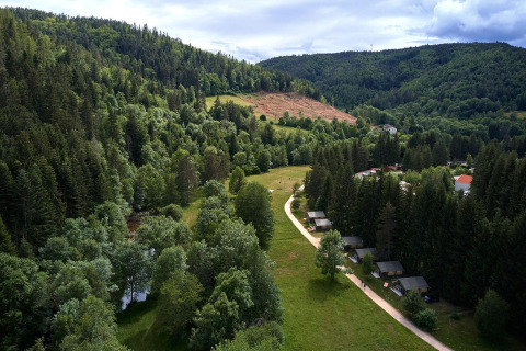 Vista aérea de un valle verde con tiendas safari en Villatent Wood, Camping de Vaubarlet, rodeado de bosque.