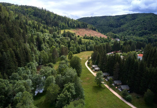 Luchtfoto van een groene vallei met safaritenten bij Villatent Wood op Camping de Vaubarlet in Frankrijk.