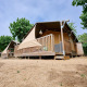 Safaritent Villatent Outback op Camping La Masia in Spanje, met houten veranda en omgeven door groen.