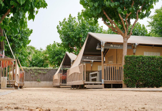 Safaritent Villatent Outback op Camping La Masia in Spanje, omgeven door groen en schaduwrijke bomen.