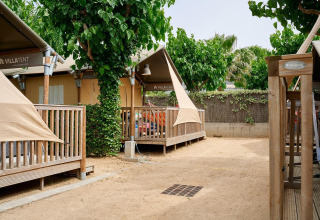 Safari tenten van Villatent Outback met houten terrassen en bomen, gelegen in een rustige campingomgeving.