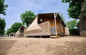 Tienda safari Villatent Outback en Camping La Masia, España, rodeada de árboles y suelo arenoso.