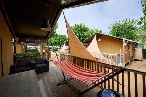 Safari tent Villatent Outback at Camping La Masia in Spain, featuring a hammock and sheltered outdoor deck.