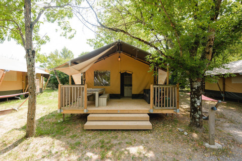 Villatent Outback al campeggio Medrose in Francia, tenda in stile lodge accogliente con veranda tra gli alberi.