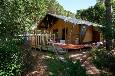 Safari tent Villatent Outback at Camping Leï Suves in France with wooden deck and hammock among trees.