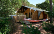 Tienda safari Villatent Outback en Camping Leï Suves, Francia, con terraza de madera y hamaca exterior.