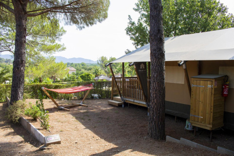 Safari tent Villatent Outback at Camping Leï Suves in France, surrounded by pine trees and a hammock.