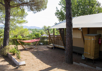 Tenda safari Villatent Outback presso Camping Leï Suves in Francia, circondata da pini e un'amaca rossa.